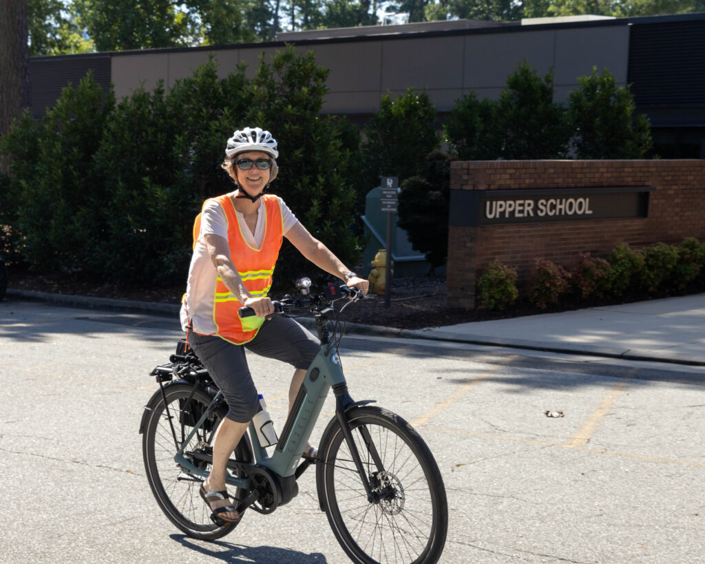 Tina Bessias riding bike in Upper School parking lot