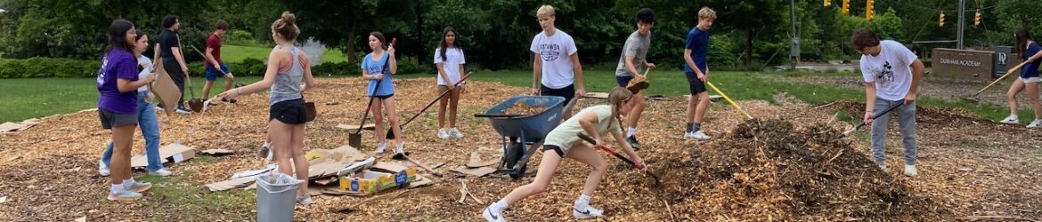 students spreading mulch at future site of garden
