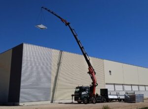 Huge crane lifting solar panels to roof of building