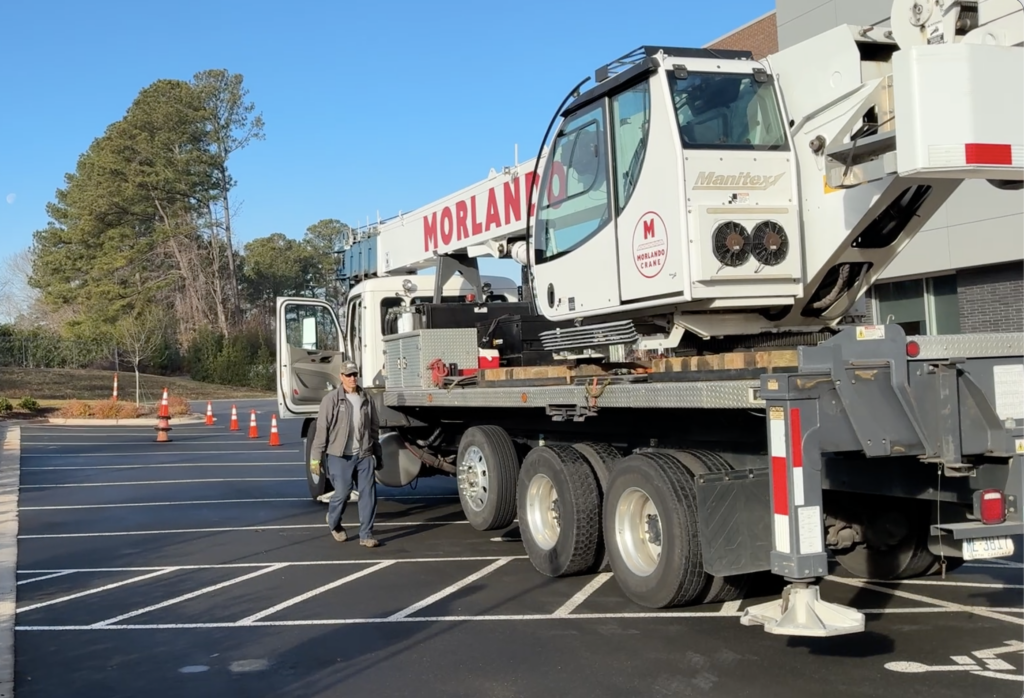Crane operator walking beside large truck with crane arm retracted above him